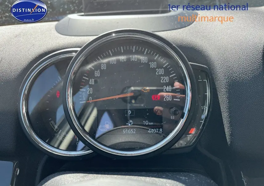 Vue rapprochée du combiné d'instruments du MINI Countryman gris, affichant le compteur de vitesse et les voyants allumés.