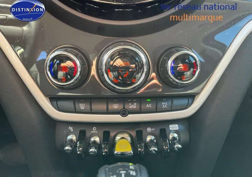 Vue rapprochée de la console centrale du MINI Countryman Moonwalk Grey, avec commandes de climatisation et bouton start/stop jaune.