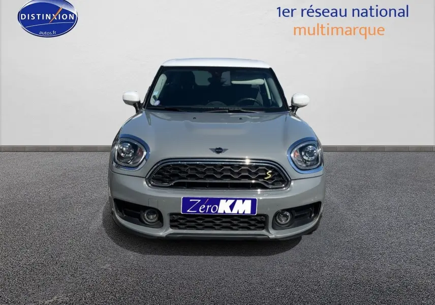 Vue avant d'une MINI Countryman Cooper SE Moonwalk Grey avec toit et rétroviseurs blancs, calandre chromée.