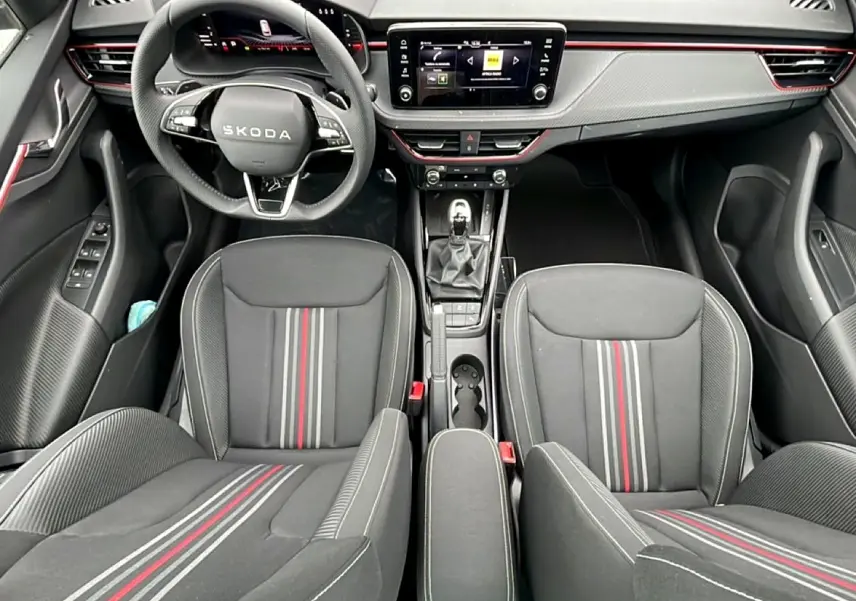 Vue intérieure frontale du Skoda Kamiq 2026 noir, sièges sport Monte Carlo avec bandes rouges et tableau de bord moderne.