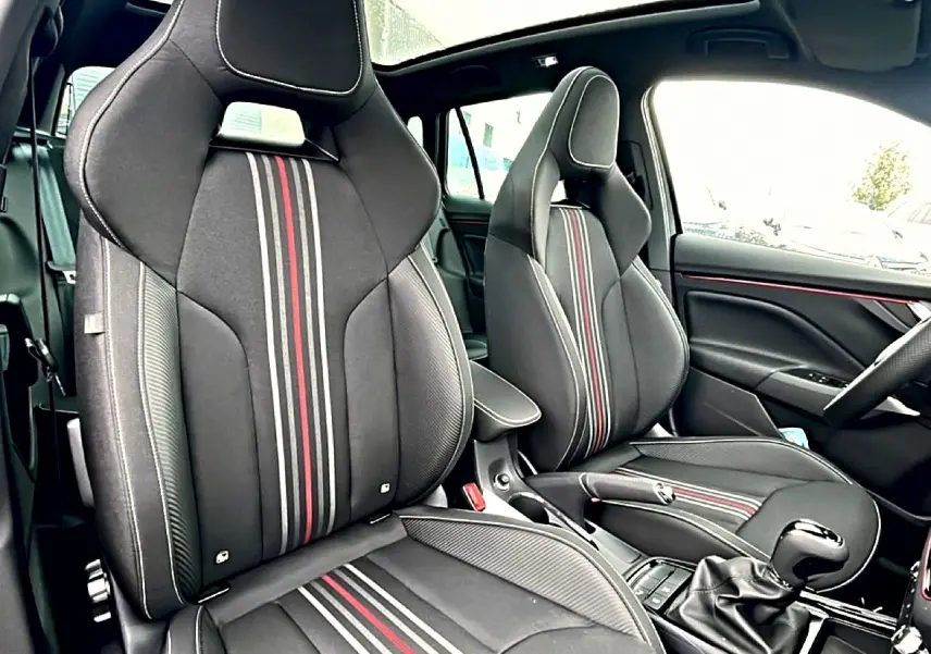 Vue intérieure du Skoda Kamiq Monte Carlo 2026 montrant les sièges sport noirs avec bandes rouges et blanches et toit panoramique.
