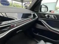 Intérieur côté passager du BMW X5 xDrive50e 2023 noir, tableau de bord moderne avec inserts métal et écran multifonction.