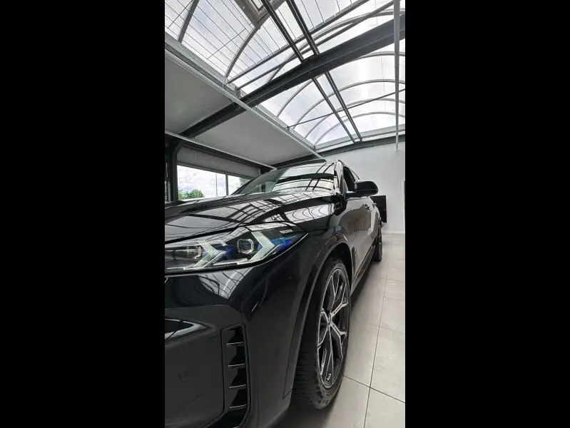 Vue 3/4 avant gauche d'un BMW X5 xDrive50e noir métallisé, mettant en valeur ses phares LED et jantes sport M.