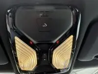 Gros plan sur le plafonnier noir brillant du BMW X5 xDrive50e 2023 avec éclairage d'ambiance doré intégré.
