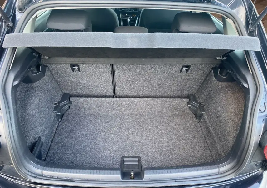 Coffre ouvert vu de l'arrière d'une Volkswagen Polo noire intense 2019, intérieur du coffre en tissu gris.