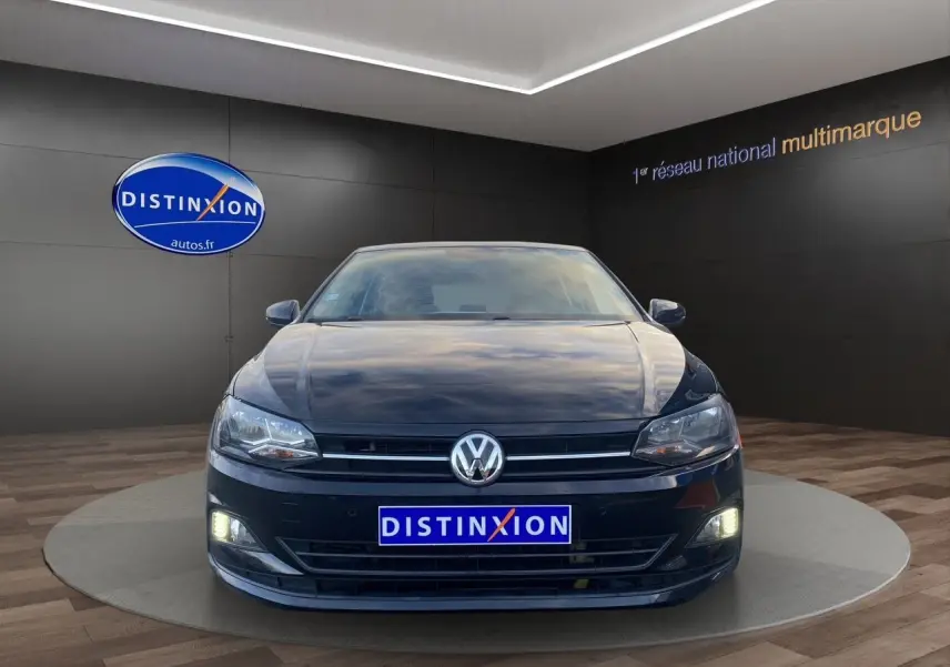 Volkswagen Polo noir intense 2019 vue de face avec phares et feux de jour allumés en showroom.