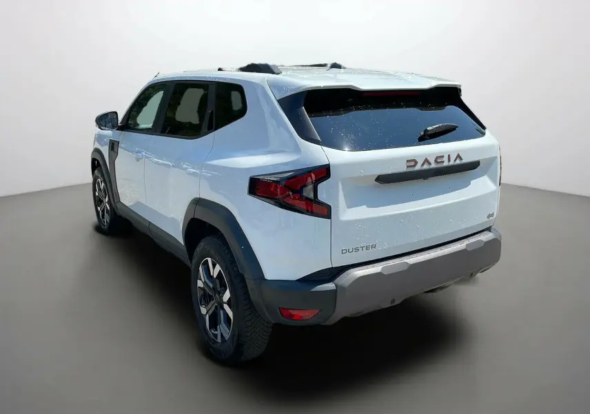 Vue 3/4 arrière droite d'un Dacia Duster blanc 2025 avec logo et feux arrière au design anguleux.