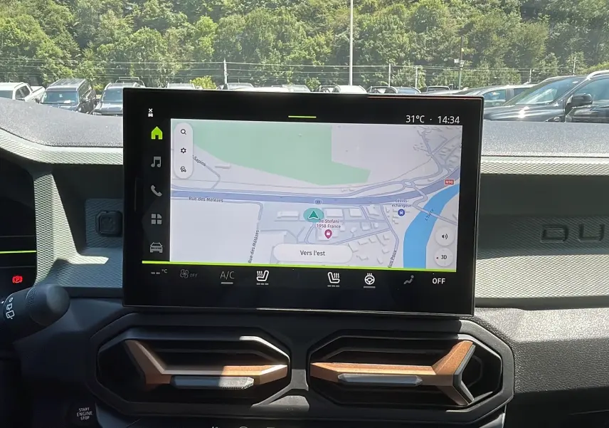 Vue intérieure du tableau de bord du Dacia Duster 2025 blanc, avec écran tactile affichant la navigation GPS.
