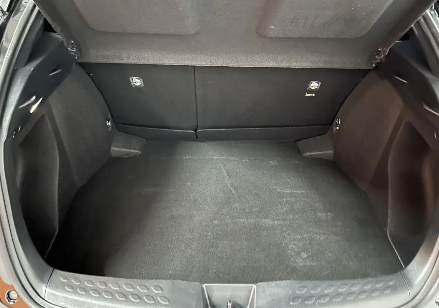 Coffre ouvert du Toyota C-HR Hybride noir métal, vue plongeante sur l'espace de chargement vide et propre.