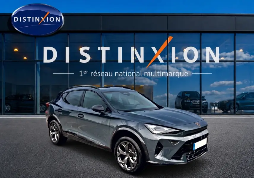 Vue 3/4 avant d'un CUPRA Formentor 1.5 etsi hybrid 150 DSG7 bleu fjord avec jantes 18 pouces devant un showroom Distinxion.