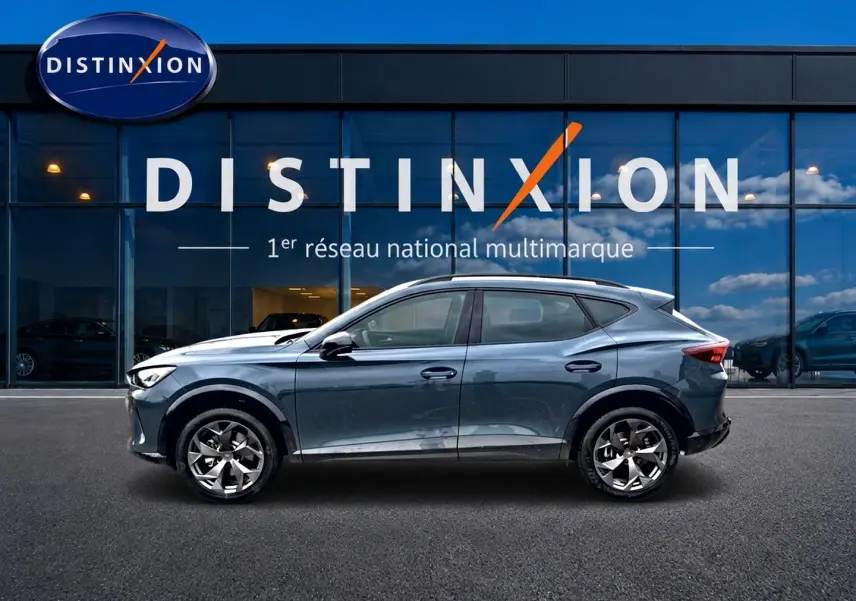 Vue de profil côté gauche d'une CUPRA Formentor 1.5 etsi hybrid 2026 en bleu fjord devant une vitrine Distinxion.