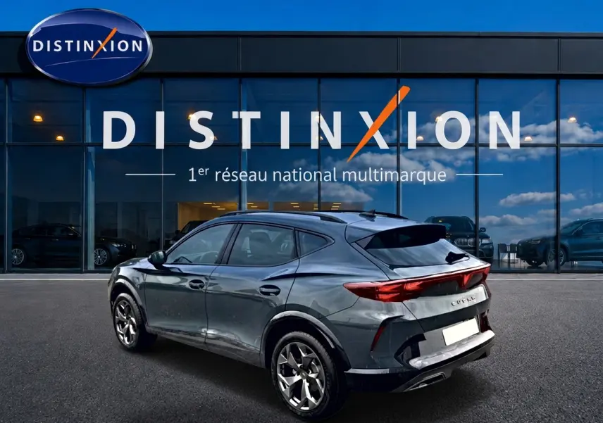 Vue 3/4 arrière d'un CUPRA Formentor bleu fjord 2026 avec feux arrière LED et jantes 18 pouces devant un showroom Distinxion.