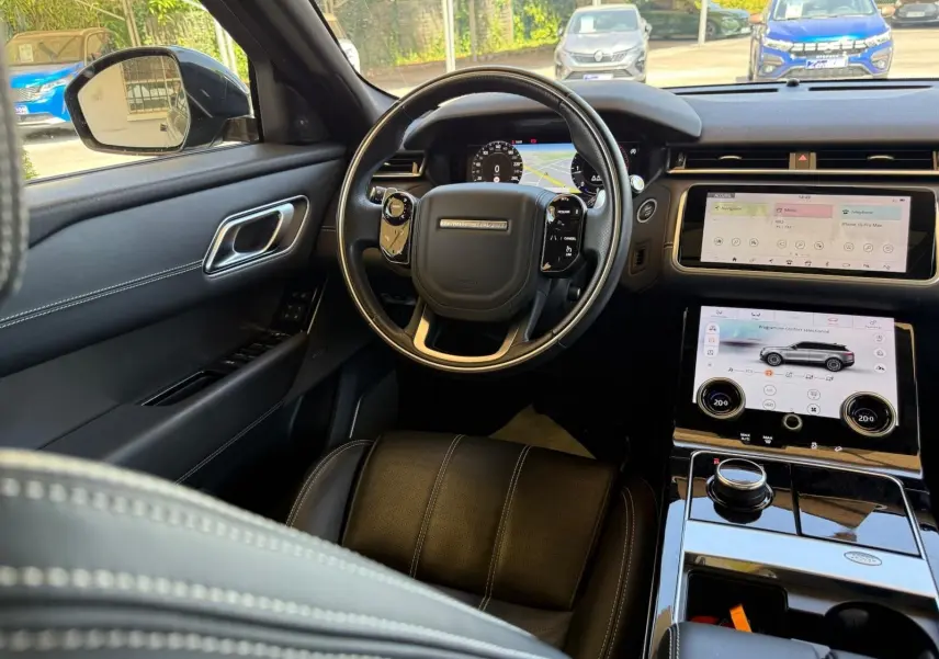 Vue intérieure côté conducteur du Range Rover Velar gris 2019, tableau de bord numérique et écran tactile central visibles.