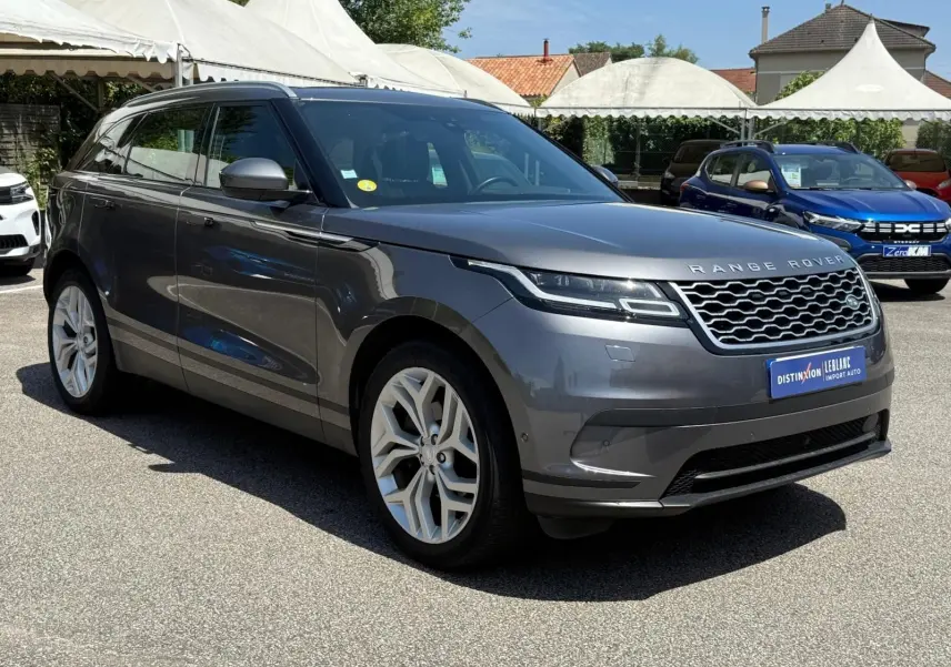 Range Rover Velar gris métallisé vu de trois quarts avant droit, avec calandre distinctive et jantes argentées.