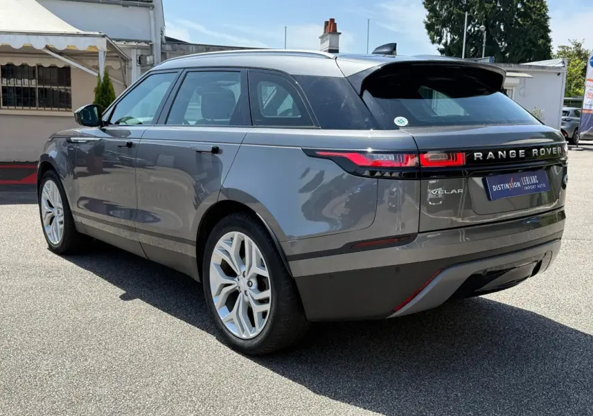 Range Rover Velar gris en 3/4 arrière droit, avec feux LED et jantes alliage distinctives visibles.