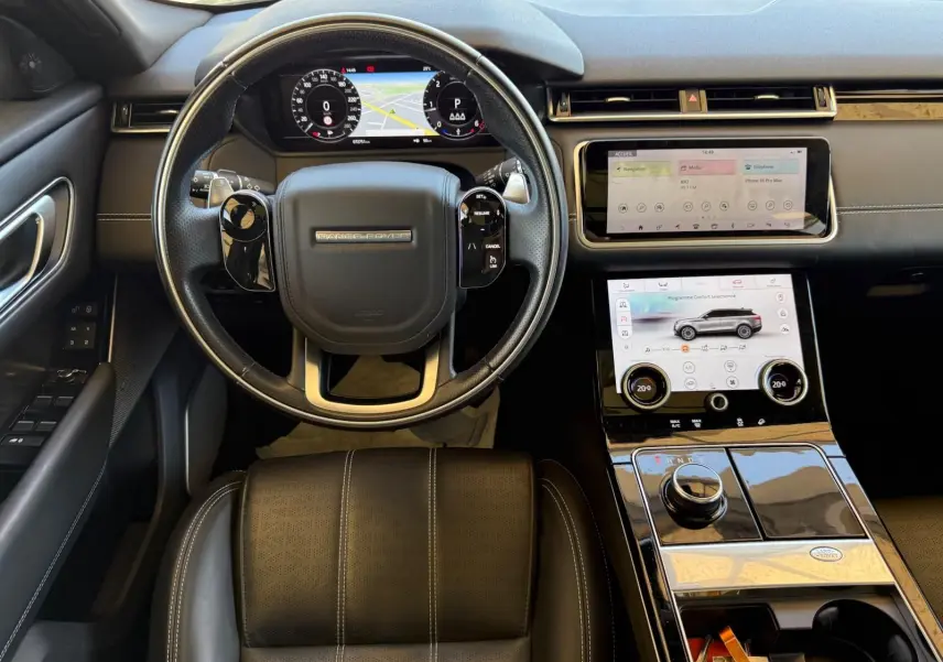 Vue intérieure du Range Rover Velar 2019 montrant le volant cuir, tableau de bord virtuel et double écran tactile central.