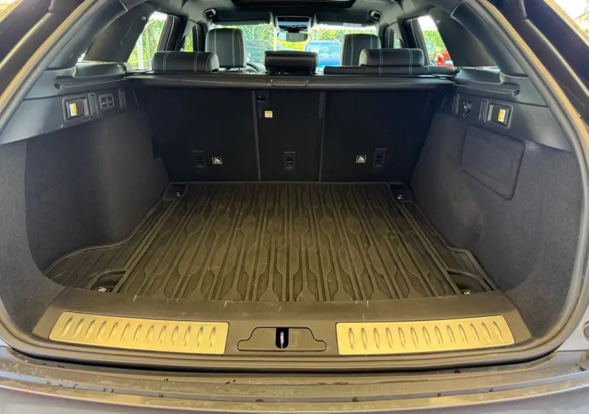 Coffre ouvert d'un Range Rover Velar gris 2019, vue arrière montrant la moquette et les sièges arrière en cuir noir.