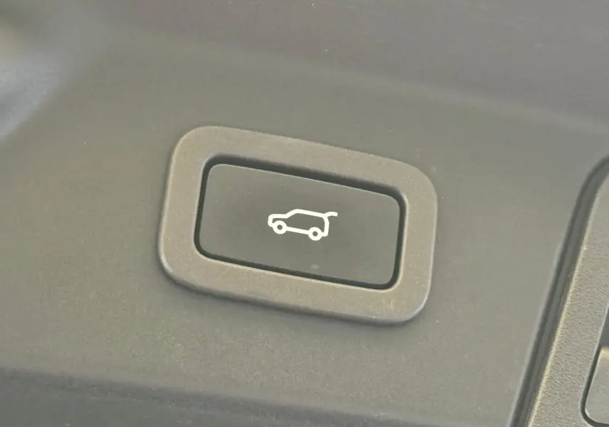 Bouton noir avec pictogramme d'ouverture du hayon, situé à l'intérieur du Range Rover Velar gris 2019.