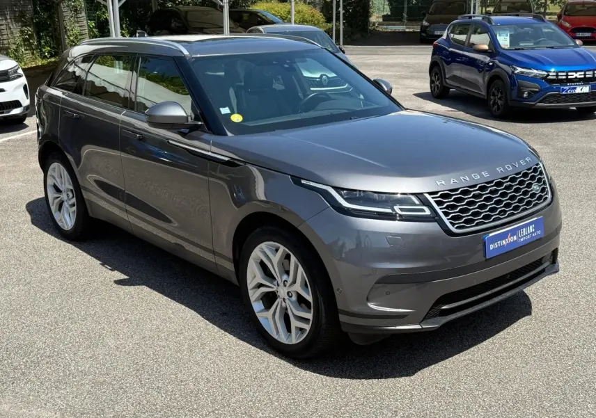 Vue 3/4 avant d'un Range Rover Velar gris métallisé, soulignant sa calandre distinctive et ses jantes argentées élégantes.