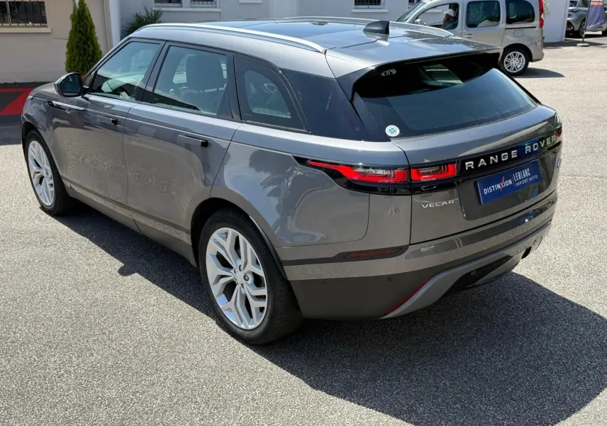 Vue 3/4 arrière droite d'un Range Rover Velar gris métallisé, soulignant ses feux arrière LED et ses jantes alliage.