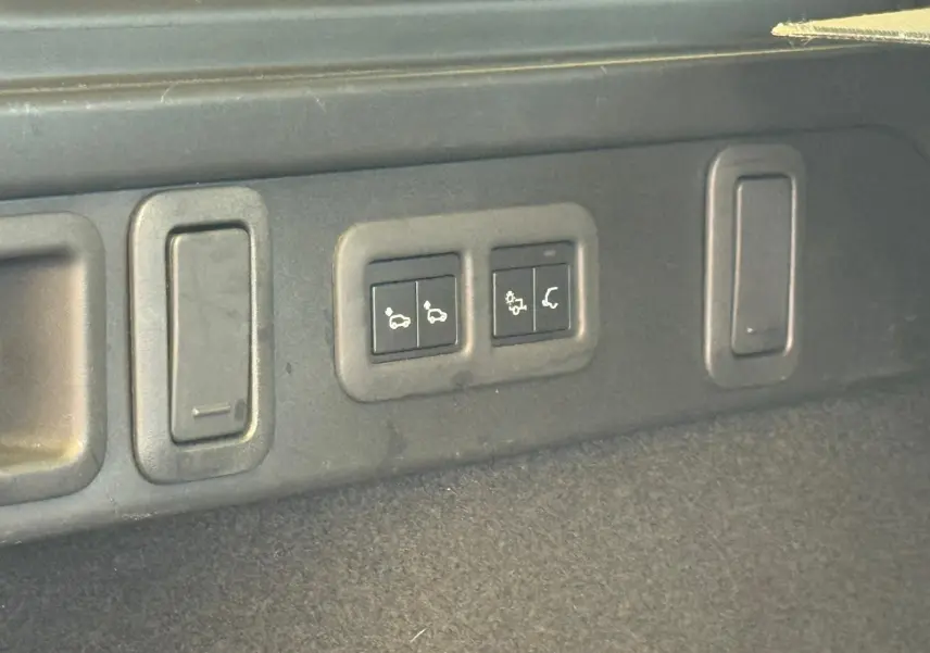 Gros plan sur les commandes du hayon électrique dans le coffre du Range Rover Velar gris 2019.