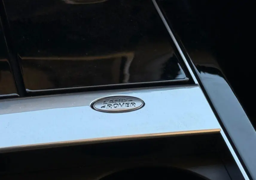 Gros plan sur le logo Land Rover chromé sur la console centrale noire brillante du Range Rover Velar gris 2019.