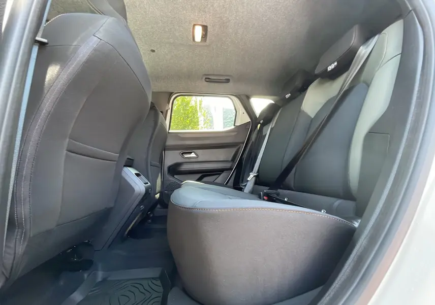 Vue intérieure arrière côté droit du Dacia Duster blanc 2025, montrant les sièges noirs avec ceinture de sécurité.