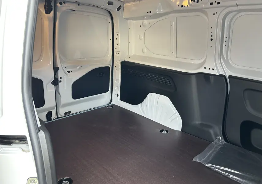 Vue intérieure arrière du Peugeot Partner Fourgon blanc 2025 avec plancher bois foncé et parois blanches.