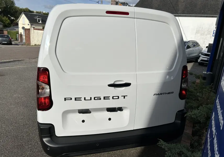Vue arrière d'un utilitaire Peugeot Partner blanc avec portes battantes et feux arrière rouges.