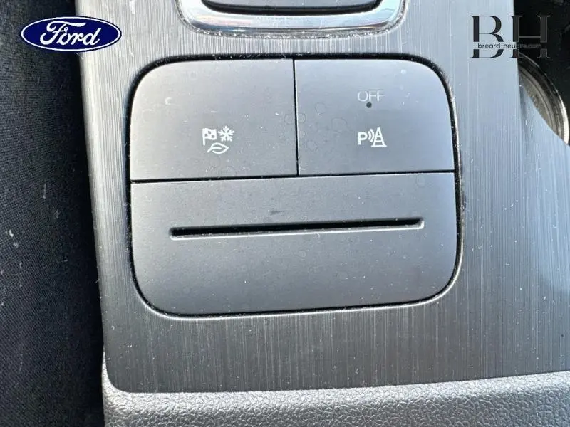 Gros plan sur les boutons de commande du système d’aide au stationnement et de la fonction éco du Ford Kuga noir Agate 2023.