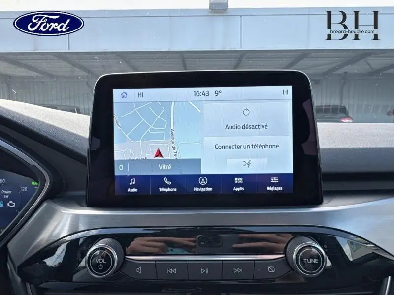 Vue rapprochée de l'écran tactile central du Ford Kuga 2023 avec interface navigation et commandes audio visibles.