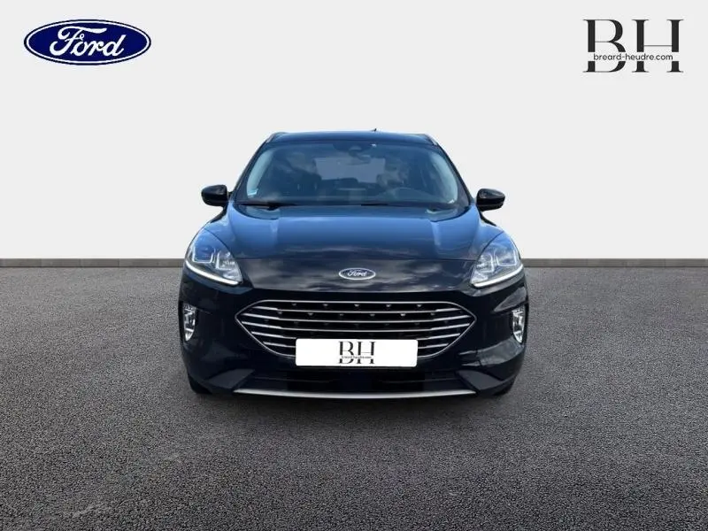 Vue frontale d'un Ford Kuga 2023 noir Agate métallisé avec calandre large chromée et phares LED allumés.