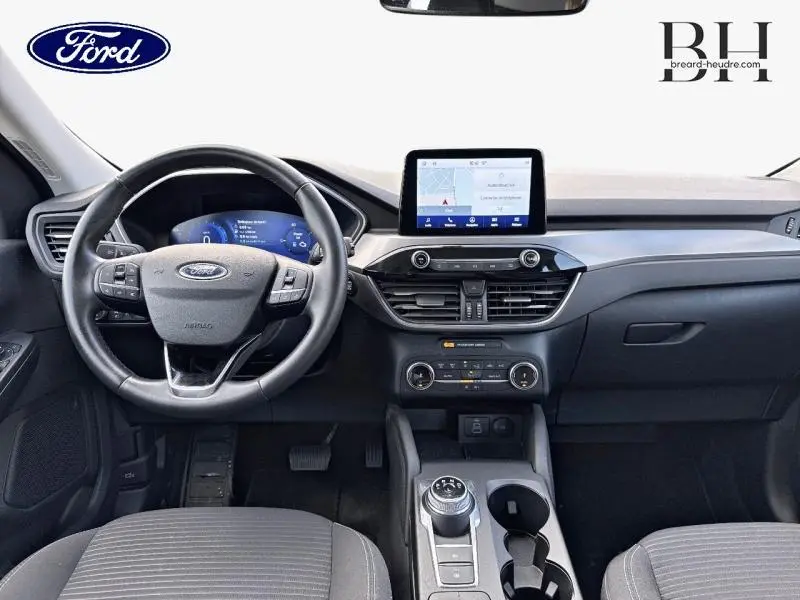 Vue intérieure avant du Ford Kuga 2023, tableau de bord noir avec écran tactile central et volant multifonction cuir.