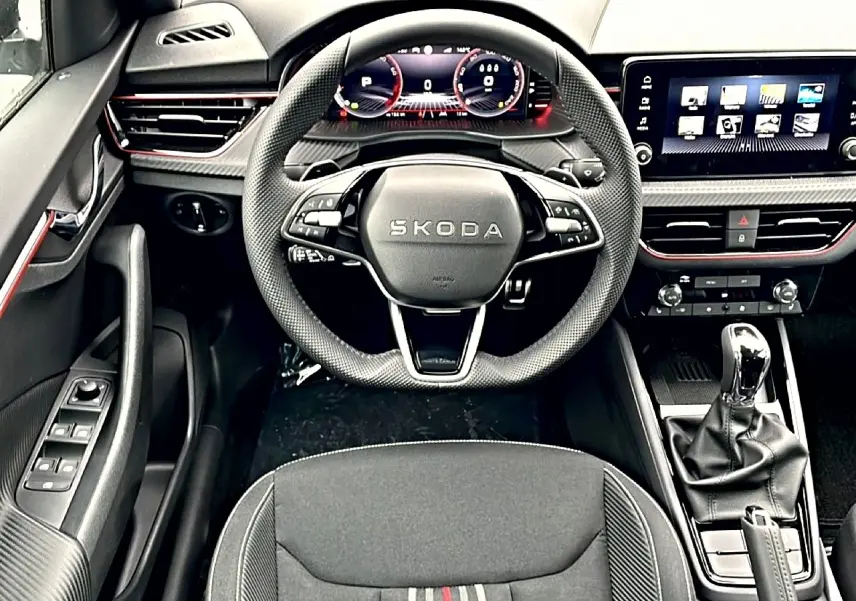 Vue intérieure frontale du poste de conduite du Skoda Kamiq blanc nacré, volant sport et écran tactile multifonction.