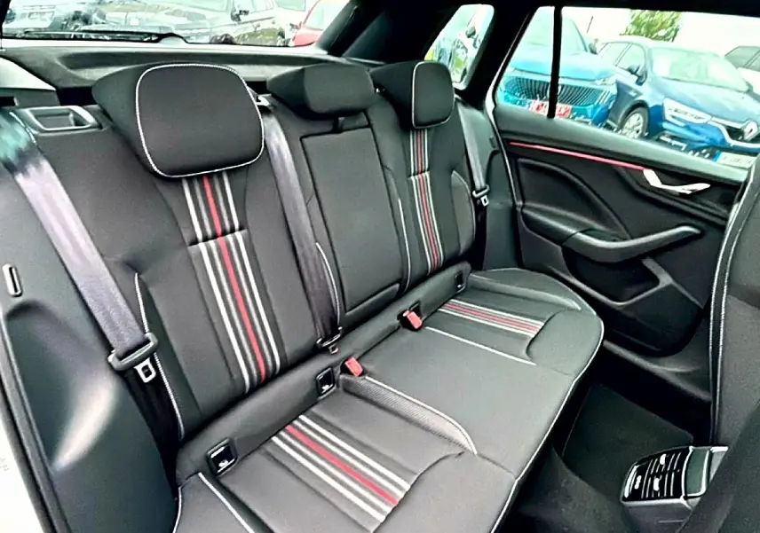 Vue intérieure arrière du Skoda Kamiq 2026, sièges sport noirs avec bandes rouges et blanches, ambiance sobre et élégante.