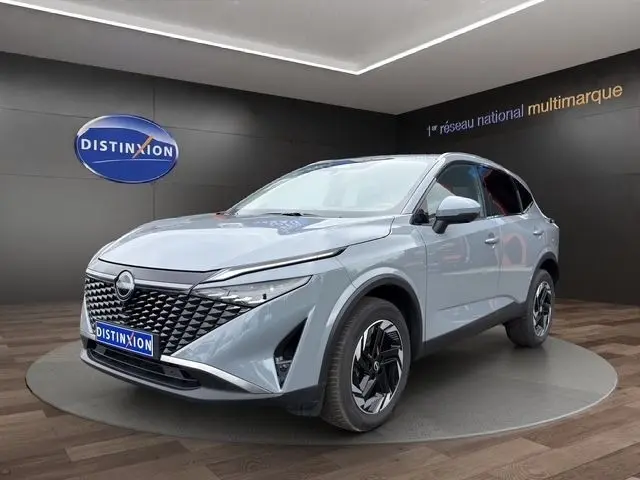 Nissan Qashqai gris foncé en 3/4 avant droit, avec calandre noire texturée et jantes noires stylisées.