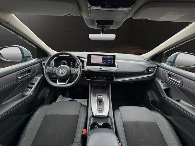 Vue intérieure avant du Nissan Qashqai 2025 gris foncé, avec tableau de bord numérique et écran tactile central.