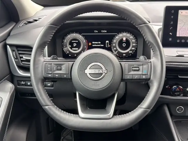 Vue frontale du volant cuir multifonctions du Nissan Qashqai 2025 avec tableau de bord numérique et écran tactile central.