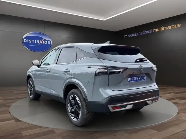 Vue 3/4 arrière d'un Nissan Qashqai gris foncé 2025 avec hayon électrique et feux arrière LED distinctifs.