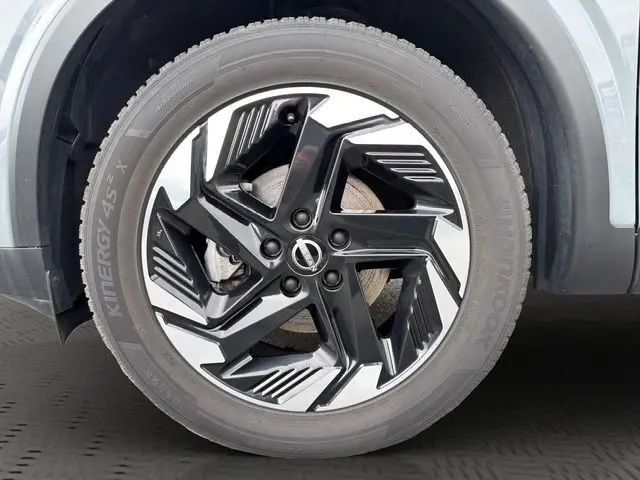 Gros plan sur la roue avant droite du Nissan Qashqai 2025 gris foncé avec jante alliage noire et argentée au design moderne.