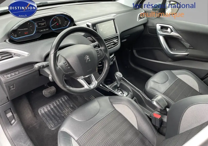 Vue intérieure côté conducteur du Peugeot 2008 blanc nacré de 2015, montrant le volant, tableau de bord et sièges en cuir noir.