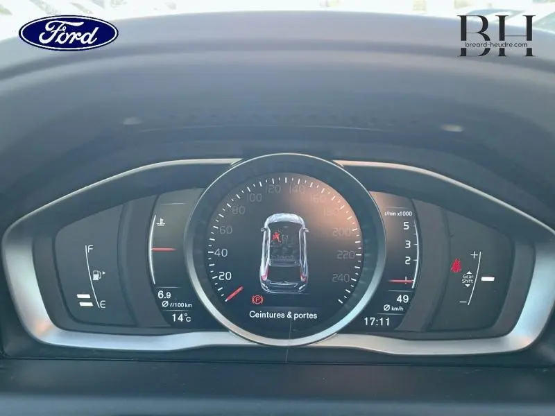 Vue rapprochée du tableau de bord numérique du Volvo XC60 gris Savile, affichant la vitesse et alertes de sécurité.