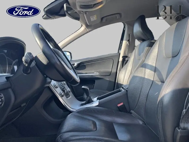 Vue intérieure côté conducteur du Volvo XC60 D3 2016 avec sièges cuir noirs et console centrale argentée.