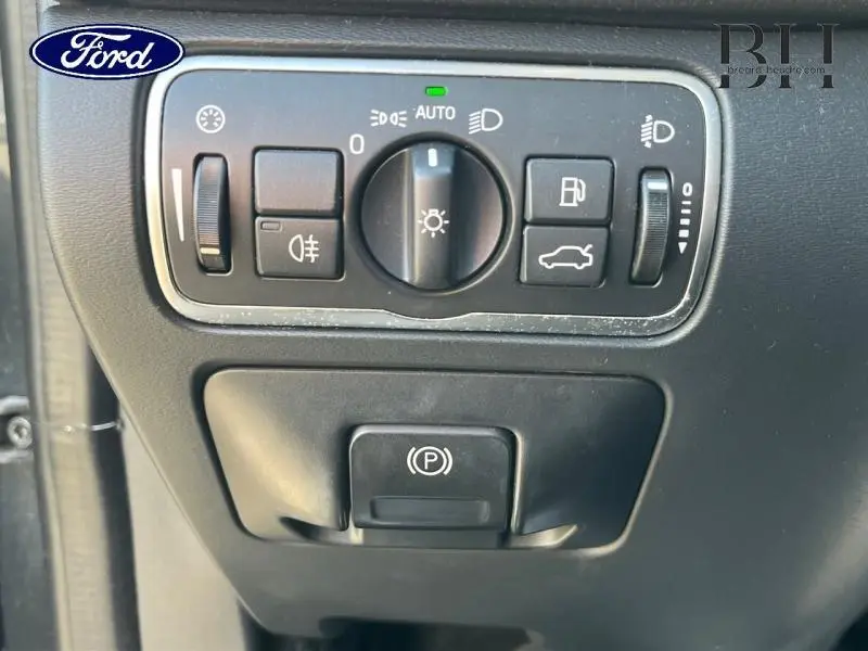 Gros plan sur les commandes d'éclairage et frein à main électrique du Volvo XC60 gris Savile, vue intérieure côté conducteur.