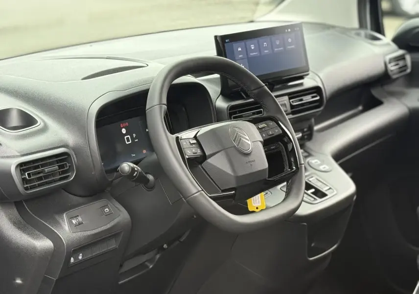 Vue intérieure du poste de conduite du Citroën Berlingo Multispace gris, avec volant multifonctions et écran tactile central.