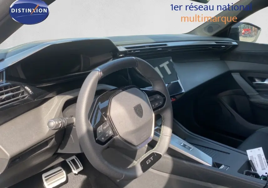 Vue intérieure côté conducteur du Peugeot 308 1.2 Hybrid blanc, avec volant GT et tableau de bord moderne noir.