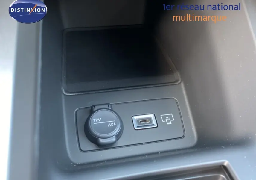 Prise 12V et port USB en gros plan dans la console centrale d’une Peugeot 308 blanche, version hybride 2026.