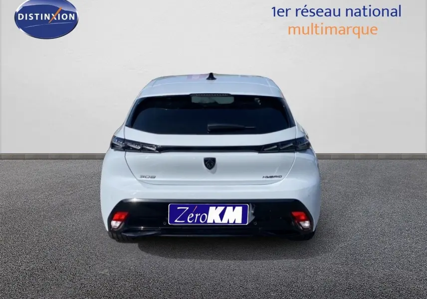 Vue arrière d'une Peugeot 308 blanche Okenite Metal, avec feux arrière fins et logo central visible.