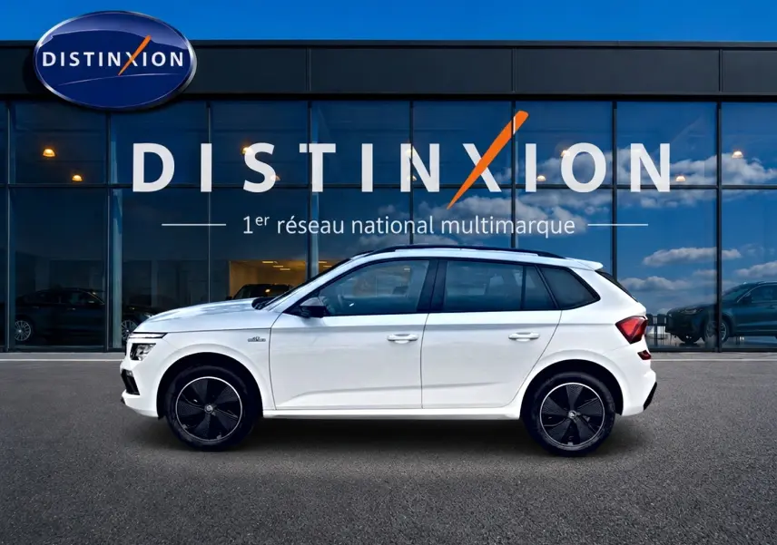 Vue de profil côté gauche d'un Skoda Kamiq blanc nacré avec jantes noires et toit panoramique en verre.