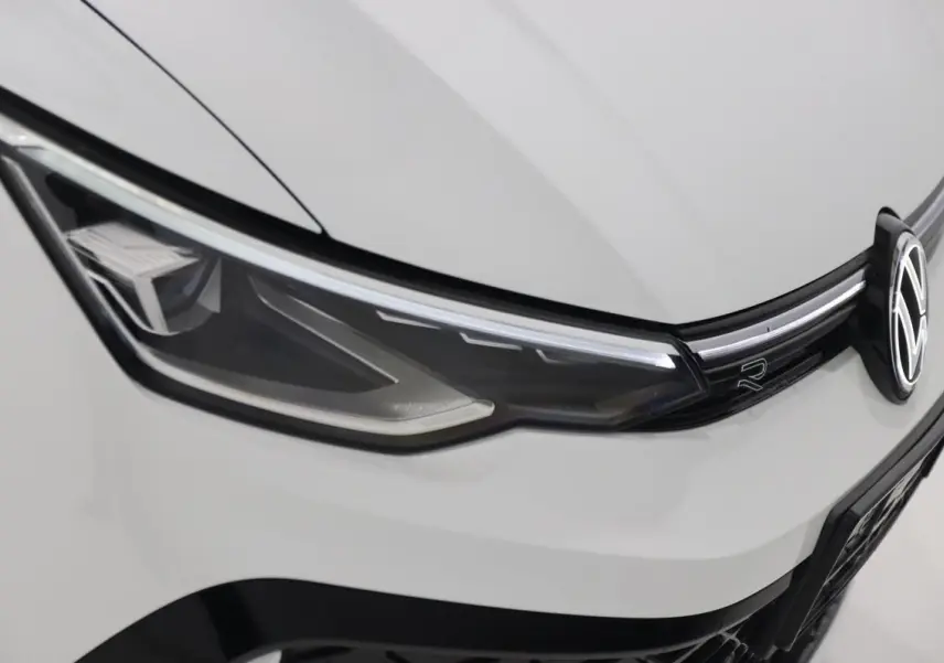 Gros plan sur le phare avant gauche blanc et calandre avec logo Volkswagen et sigle R-LINE.
